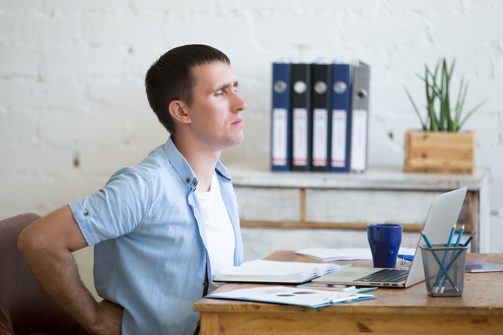 Office worker with backache representative image for workplace stress health news